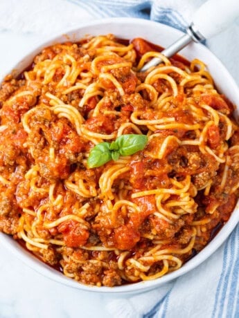 A big white bowl full of Instant Pot Spaghetti with a basil leaf in the middle
