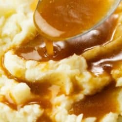 Image of brown gravy being drizzled over a pile of mashed potatoes.