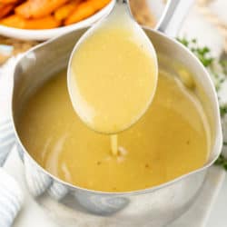 A saucepan filled with homemade Chicken Gravy with a big spoon Scooping it up.