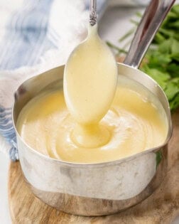 A spoon scooping out homemade Cream of Chicken Soup from a saucepan.