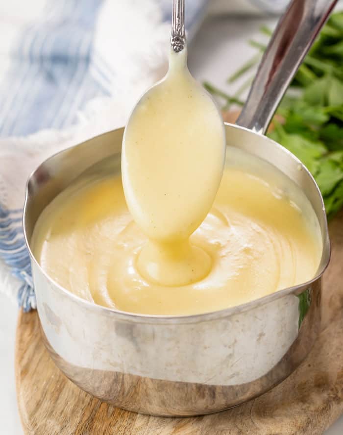 A spoon scooping out homemade Cream of Chicken Soup from a saucepan.