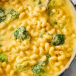 A dutch oven with creamy Broccoli Mac and Cheese with a spoon in it.