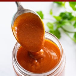 Enchilada Sauce in a jar with a spoon scooping it up.