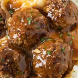 Meatballs on a plate with mashed potatoes with gravy.