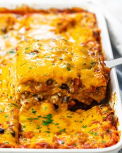 A casserole dish filled with Taco Lasagna that's being pulled up with a spatula.