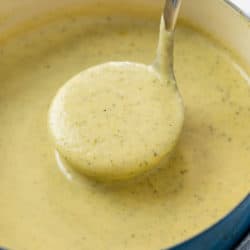 A soup pot filled with a ladle scooping up creamy zucchini soup.