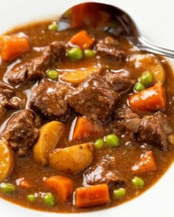 A white bowl filled with Slow Cooker Beef Stew with a spoon in the background.