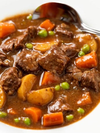 A white bowl filled with Slow Cooker Beef Stew with a spoon in the background.