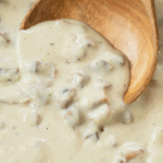 A close up view of a wooden spoon scooping up homemade condensed cream of mushroom soup