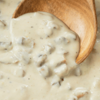 A close up view of a wooden spoon scooping up homemade condensed cream of mushroom soup