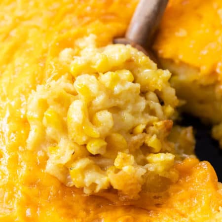 A wooden spoon scooping up Corn Casserole from a skillet.