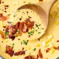 A soup pot filled with creamy Corn Chowder topped with bacon and chives.