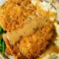 Crispy Country Fried Chicken Topped with gravy over a pile of mashed potatoes.