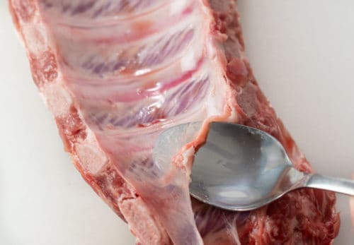 A spoon underneath the membrane on baby back ribs.