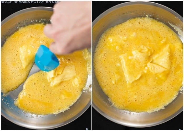 A spatula dragging fluffy scrambled eggs into the middle of a pan while they cook.