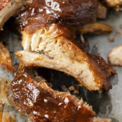 Slow Cooker Ribs topped with BBQ Sauce on parchment paper.
