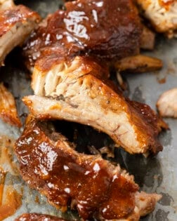 Slow Cooker Ribs topped with BBQ Sauce on parchment paper.