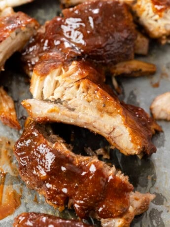 Slow Cooker Ribs topped with BBQ Sauce on parchment paper.