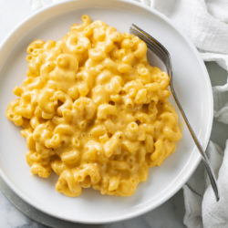 Creamy Mac and Cheese on a white plate with a fork on the side.