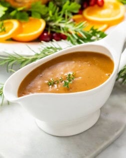 Thick brown turkey gravy in a gravy boat topped with fresh thyme.