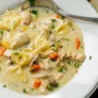 Turkey noodle soup with farfalle noodles in a white bowl with a spoon.