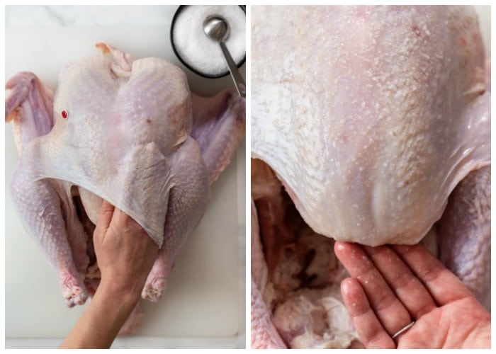 A hand massaging salt on a turkey for dry brining.