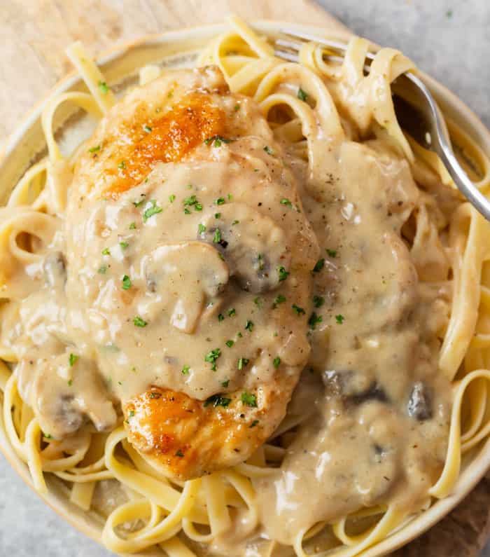 A plate with fettuccine noodles topped with creamy Chicken Stroganoff.