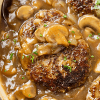 Salisbury Steak in a skillet topped with mushroom gravy and fresh parsley.