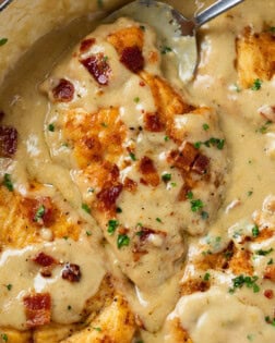 Smothered Chicken covered with gravy and topped with crispy bacon and parsley.