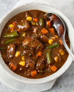 A bowl filled with Beef Vegetable Soup with a spoon in it.