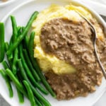 Hamburger Gravy over mashed potatoes with green beans on the side.