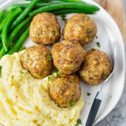 Turkey meatballs on a plate with mashed potatoes and green beans.