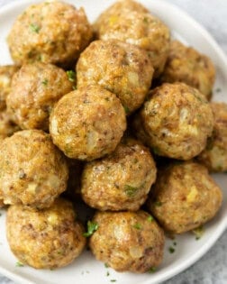 A pile of turkey meatballs on a white plate with parsley.