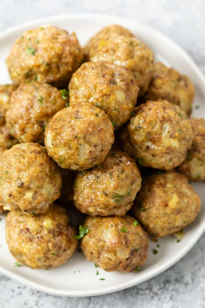 A pile of turkey meatballs on a white plate with parsley.