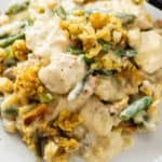 A plate with chicken and stuffing casserole with green beans and creamy sauce.