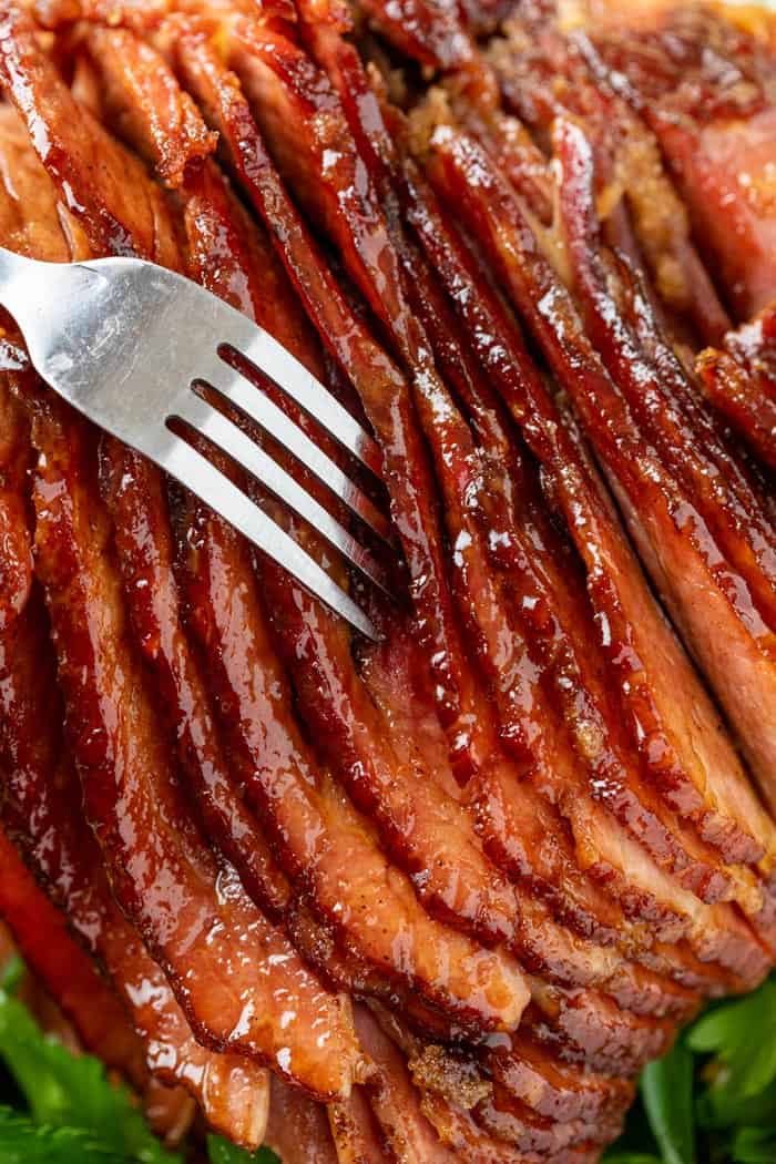 A fork pulling up glazed ham.