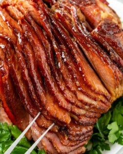 A platter topped with glazed ham on top of parsley.