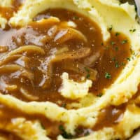 Onion Gravy over a pile of mashed potatoes with roughly chopped parsley on top.