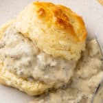 A buttermilk biscuit sliced in half with Sausage Gravy in the middle and on the side.