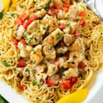 Chicken Scampi with lemon wedges and diced tomatoes with thin spaghetti and chicken.