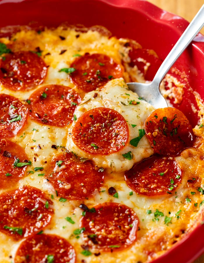 A spoon scooping up cheesy Pizza Dip with mozzarella cheese and Pepperoni.