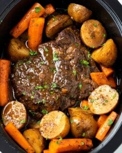 A Crock Pot Roast in a Crock with Potatoes, potatoes, and gravy.