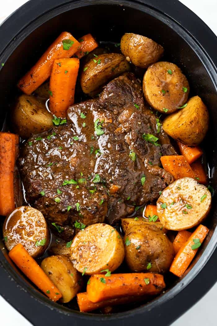 A Crock Pot Roast in a Crock with Potatoes, potatoes, and gravy.