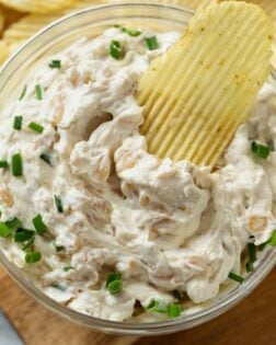 A ruffled Chip dipped into French Onion Dip with chives on top.