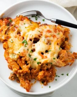 Cheesy Pasta Bake on top of a white plate with a fork and fresh parsley.