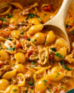 A wooden spoon scooping up taco pasta from a pot.