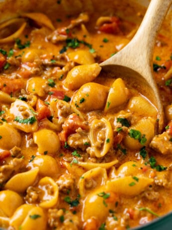 A wooden spoon scooping up taco pasta from a pot.