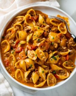 Taco Pasta with shells on a white plate in a creamy red sauce with tomatoes.