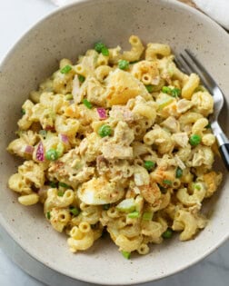 A bowl with Tuna Pasta Salad with creamy macaroni, eggs, tuna, and peas.