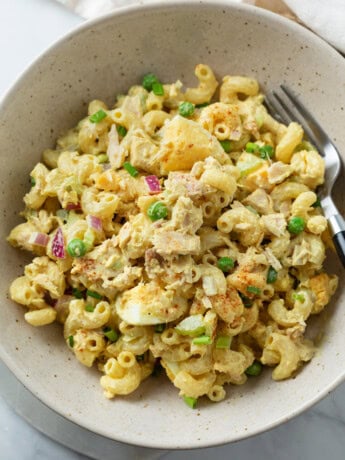 A bowl with Tuna Pasta Salad with creamy macaroni, eggs, tuna, and peas.